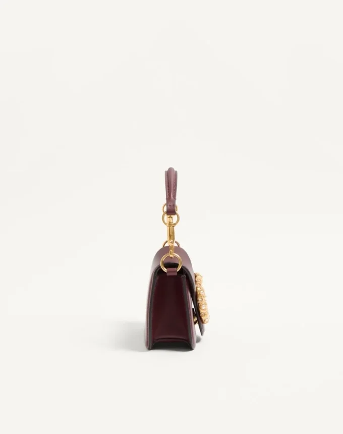 Petit sac à bandoulière Valentino Garavani Locò en cuir de veau avec logo bijou Petit sac à bandoulière Valentino Garavani Locò en cuir de veau avec logo bijou