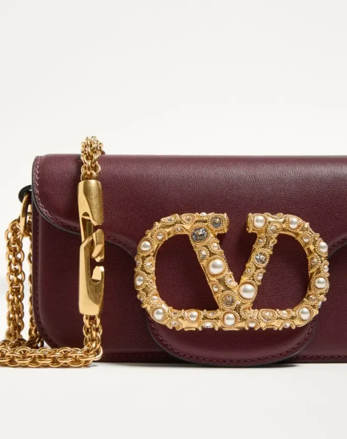 Petit sac à bandoulière Valentino Garavani Locò en cuir de veau avec logo bijou Petit sac à bandoulière Valentino Garavani Locò en cuir de veau avec logo bijou